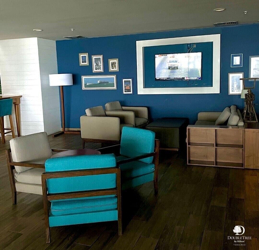 A modern living room with a blue accent wall, a flat-screen TV, and a wooden sideboard.
