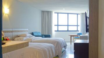 Een hotelkamer met twee bedden, een bureau, een stoel, een televisie en een groot raam.