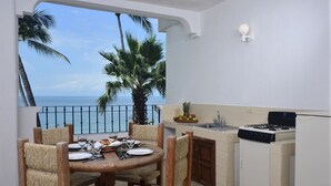 A dining area with a view of the sea, a kitchen with a gas stove, and a fruit bowl on the counter. - Emperador Vallarta Beachfront Hotel and Suites (Puerto Vallarta)