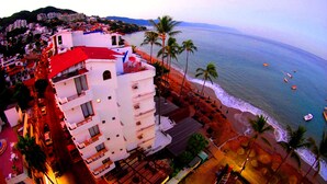 A coastal hotel with multiple floors, a red roof, and a beach view. - Emperador Vallarta Beachfront Hotel and Suites (Puerto Vallarta)