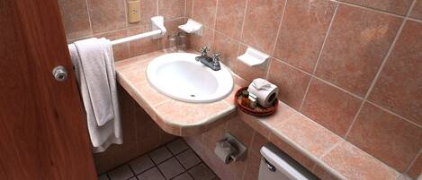 Un baño pequeño con lavamanos, inodoro y barra para toallas.