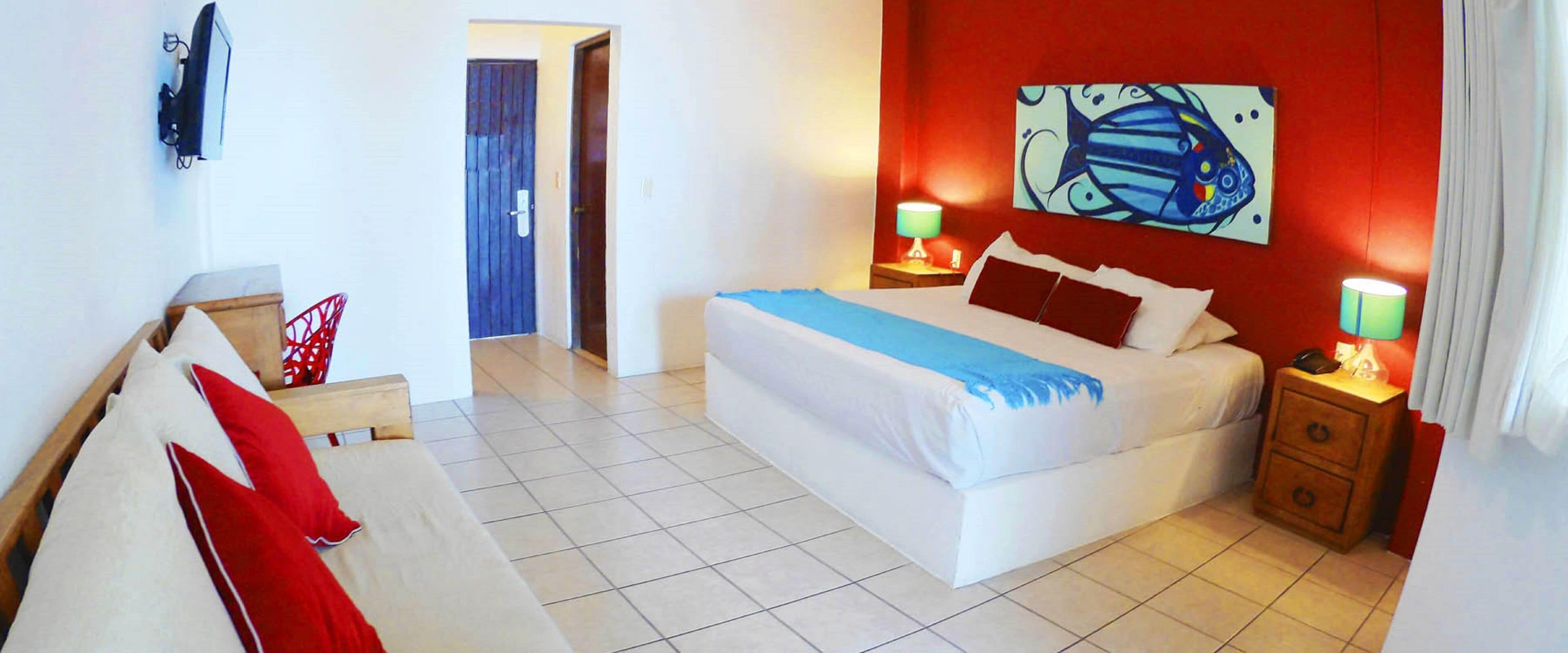 A hotel room with a bed, bedside tables, a TV, and a painting on the wall.