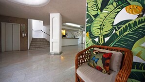 A lobby with a staircase, a reception desk, and a wicker chair with a colorful cushion. - Emperador Vallarta Beachfront Hotel and Suites (Puerto Vallarta)