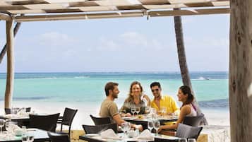 Dine al fresco with a view of the ocean from our outdoor dining area, shaded by a pergola.