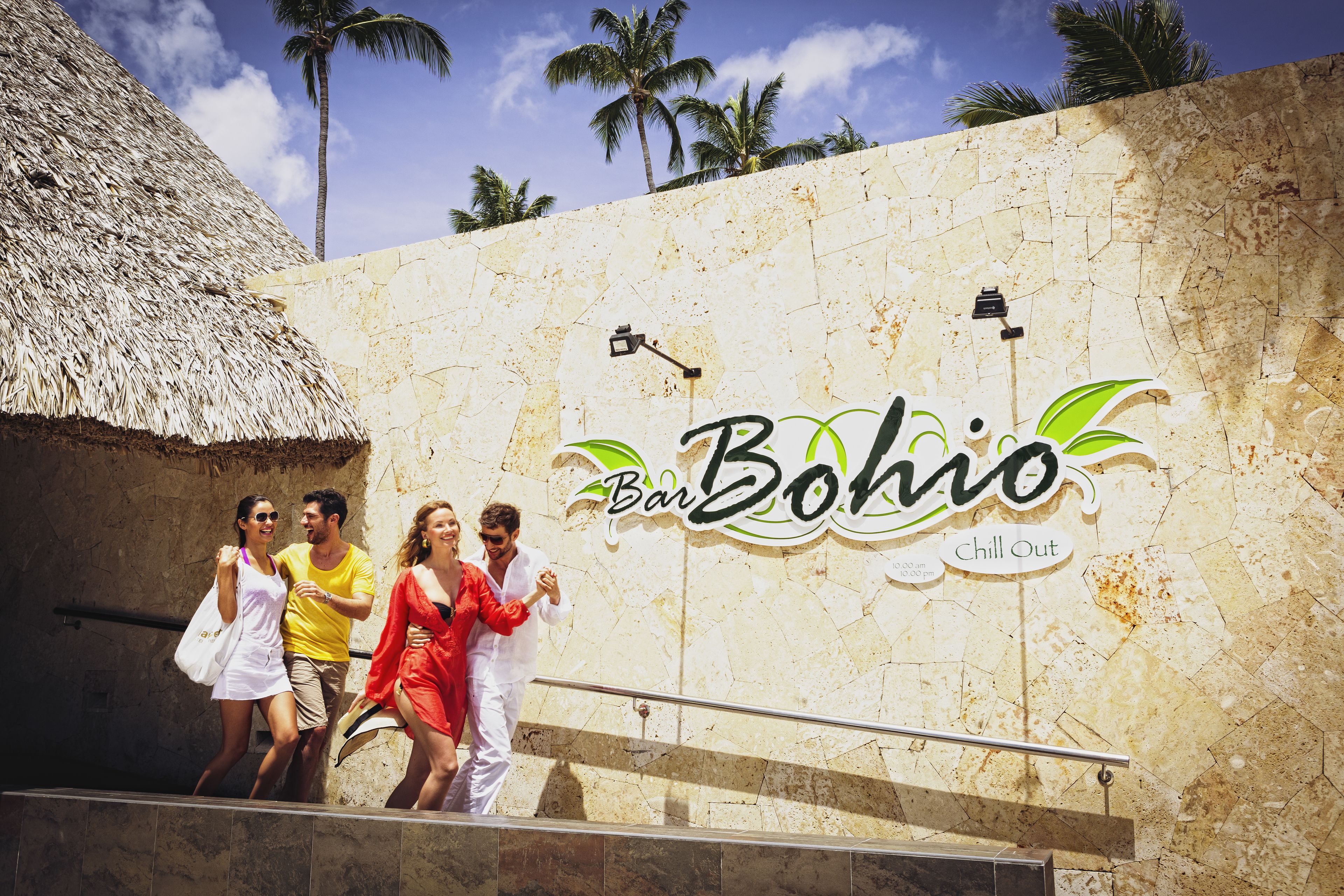 A group of people walking past a building with a sign that reads "Bar Bohol Chill Out."