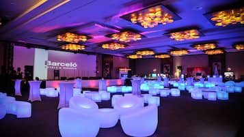 Een ruime evenementenruimte met verlichte zitplaatsen en een podium, waarschijnlijk voor conferenties of evenementen.