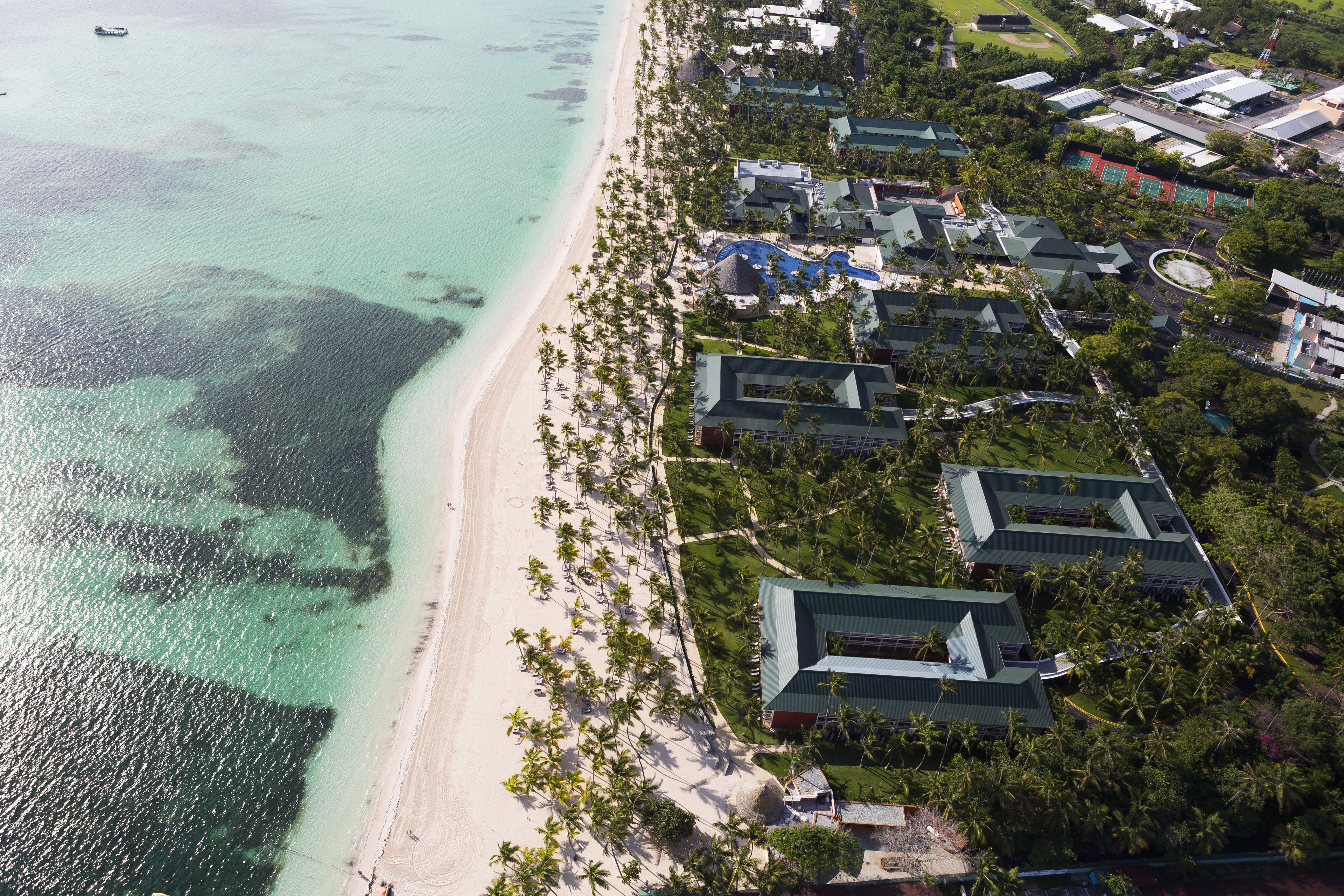 Vue aérienne d’un complexe hôtelier avec des propriétés situées en bord de mer, une piscine et un terrain de golf.