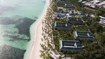 Vue aérienne d’un complexe hôtelier avec des propriétés situées en bord de mer, une piscine et un terrain de golf.