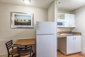 Una cocina compacta con refrigerador, microondas y un comedor con mesa y sillas.