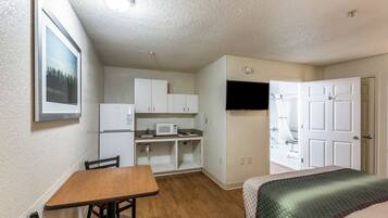 A compact room with a kitchenette, a dining area, and a bed.