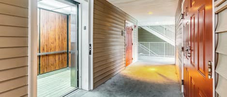 Un couloir avec une porte en bois, un portail en métal et un escalier menant à un niveau supérieur.