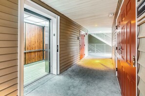 A corridor with a wooden door, a metal gate, and a staircase leading to an upper level. - HomeTowne Studios By Red Roof Gainesville, GA (Gainesville)