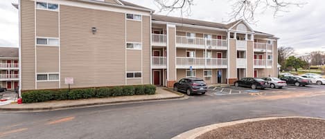A multi-story building with a parking lot in front.