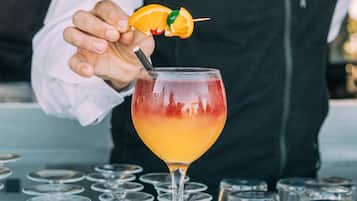 A bartender preparing a cocktail with a lime slice garnish.