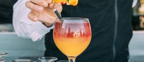 A bartender preparing a cocktail with a lime slice garnish.