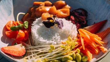 A bowl of rice with vegetables and a flower on top.