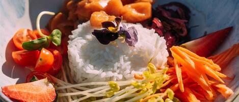 A bowl of rice with vegetables and a flower on top.