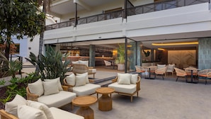A spacious outdoor seating area with wicker furniture and a bar in the background. - Radisson Resort & Residences Tenerife - Adults Only (Puerto de la Cruz)