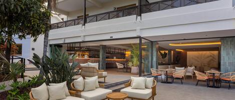 Un amplio espacio al aire libre con mobiliario de mimbre y un bar al fondo.