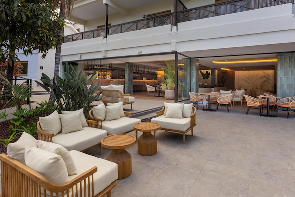 A spacious outdoor seating area with wicker furniture and a bar in the background.