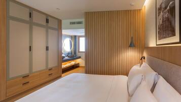 Habitación de hotel con una cama grande, un armario de madera, un tocador con espejo y un cuadro enmarcado en la pared.
