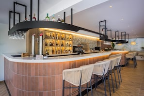 A modern bar area with a curved counter, multiple liquor bottles, and bar stools.