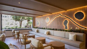A modern lounge area with a sofa, chairs, and round tables. - Radisson Resort & Residences Tenerife - Adults Only (Puerto de la Cruz)