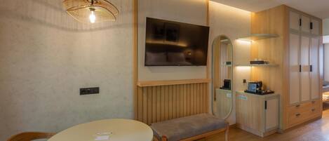 Ein modernes Zimmer mit einem runden Tisch, einer Bank, einem Fernseher und Holzschränken.