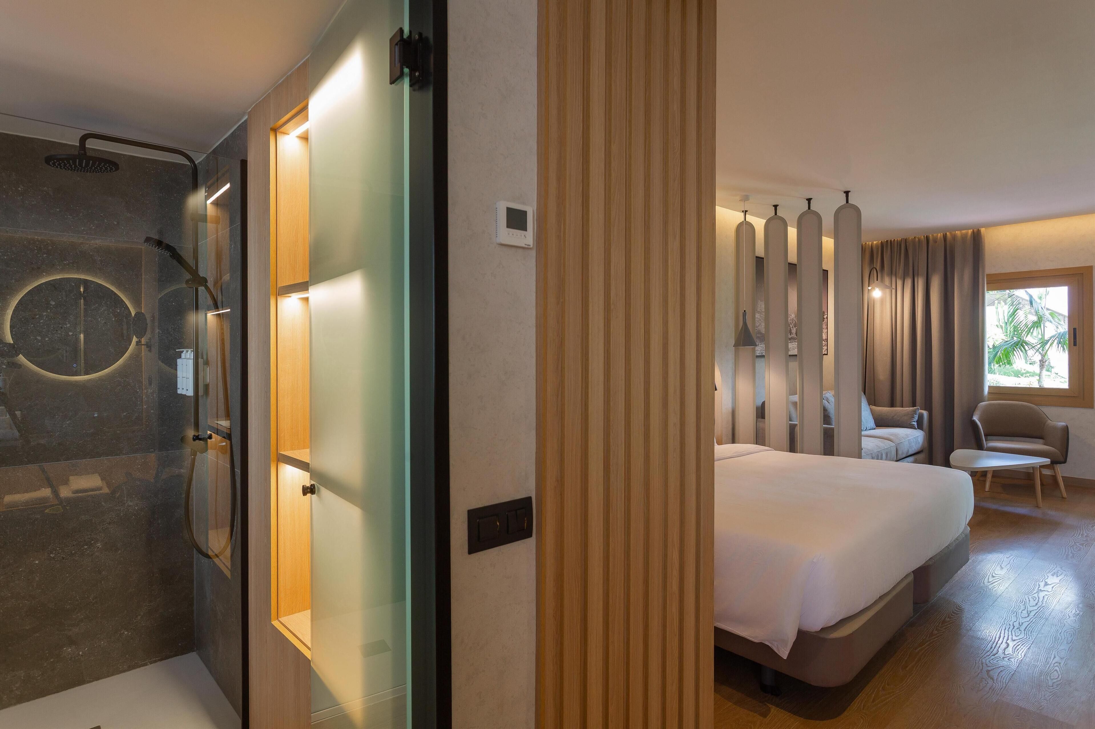 Una habitación de hotel moderna con ducha, cama, zona de estar y ventana con cortinas.
