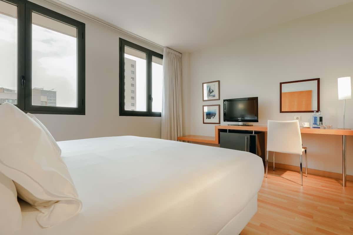 Habitación de hotel con una cama grande, un escritorio con computadora, televisión y cuadros en la pared.