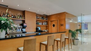 A bar area with a wooden counter, multiple liquor bottles, a coffee machine, and several bar stools.