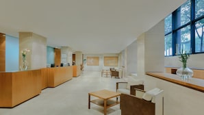 Eine geräumige Lobby mit Empfangsschalter, Sitzgelegenheiten und großen Fenstern.