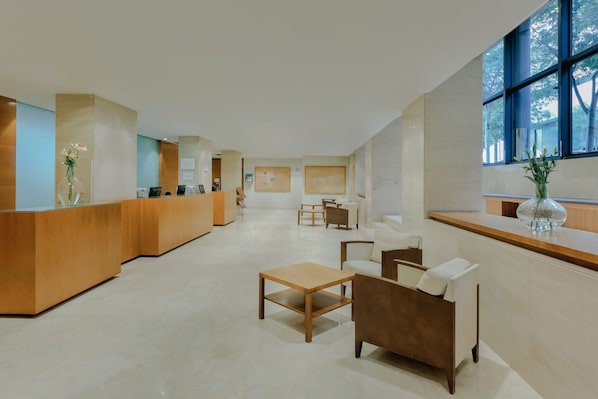 A spacious lobby with a reception desk, seating area, and large windows.