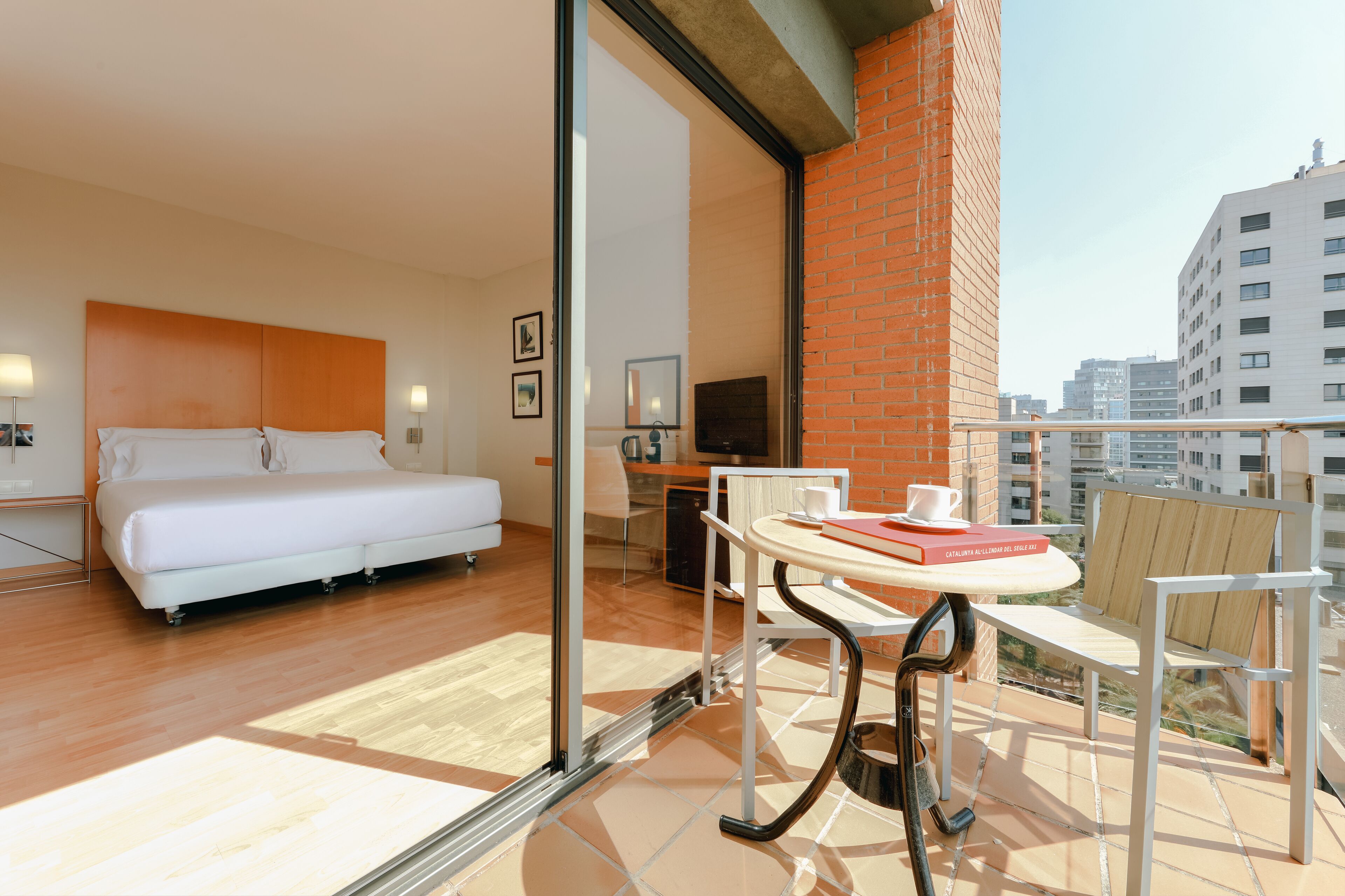 Una habitación de hotel moderna con cama, escritorio y balcón con mesa y sillas.