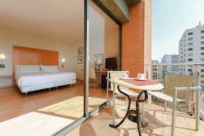 A modern hotel room with a bed, a desk, and a balcony with a table and chairs. - Catalonia Barcelona Beach (Barcelona)
