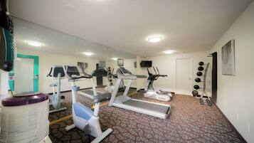 A gym with treadmills, elliptical machines, and a weight rack.
