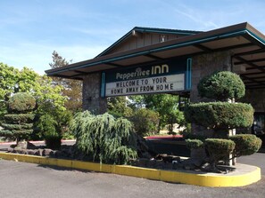 A sign for Peppertree Inn with a welcoming message and a stone building facade.