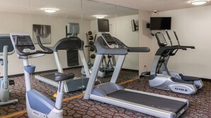 A gym with treadmills, ellipticals, and a mirrored wall. - PepperTree Inn (Beaverton)