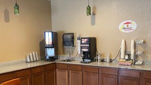 Un área de desayuno con una mesa, sillas, una cafetera, un televisor y un cartel de desayuno Superstart.
