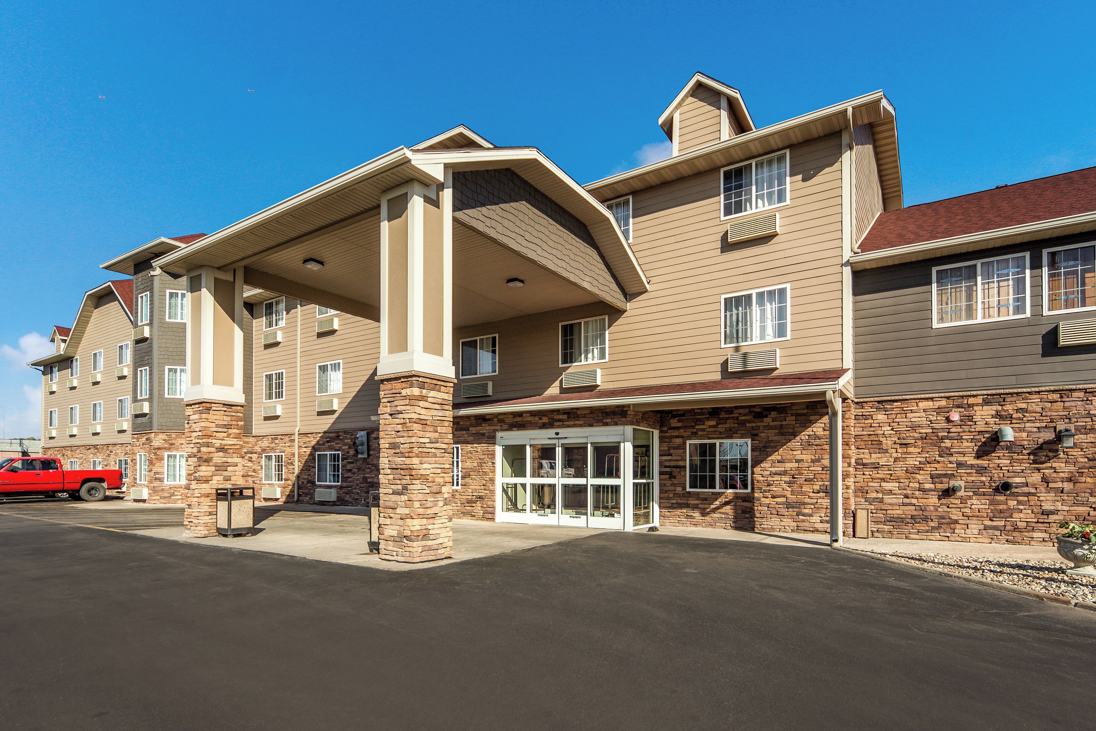 A multi-story hotel with a stone facade, a covered entrance, and a red truck parked in front.
