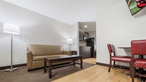 Un salon moderne comprenant un canapé, une table basse, un lampadaire et un coin repas avec une chaise et une table.
