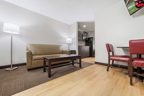 Un salon moderne comprenant un canapé, une table basse, un lampadaire et un coin repas avec une chaise et une table.