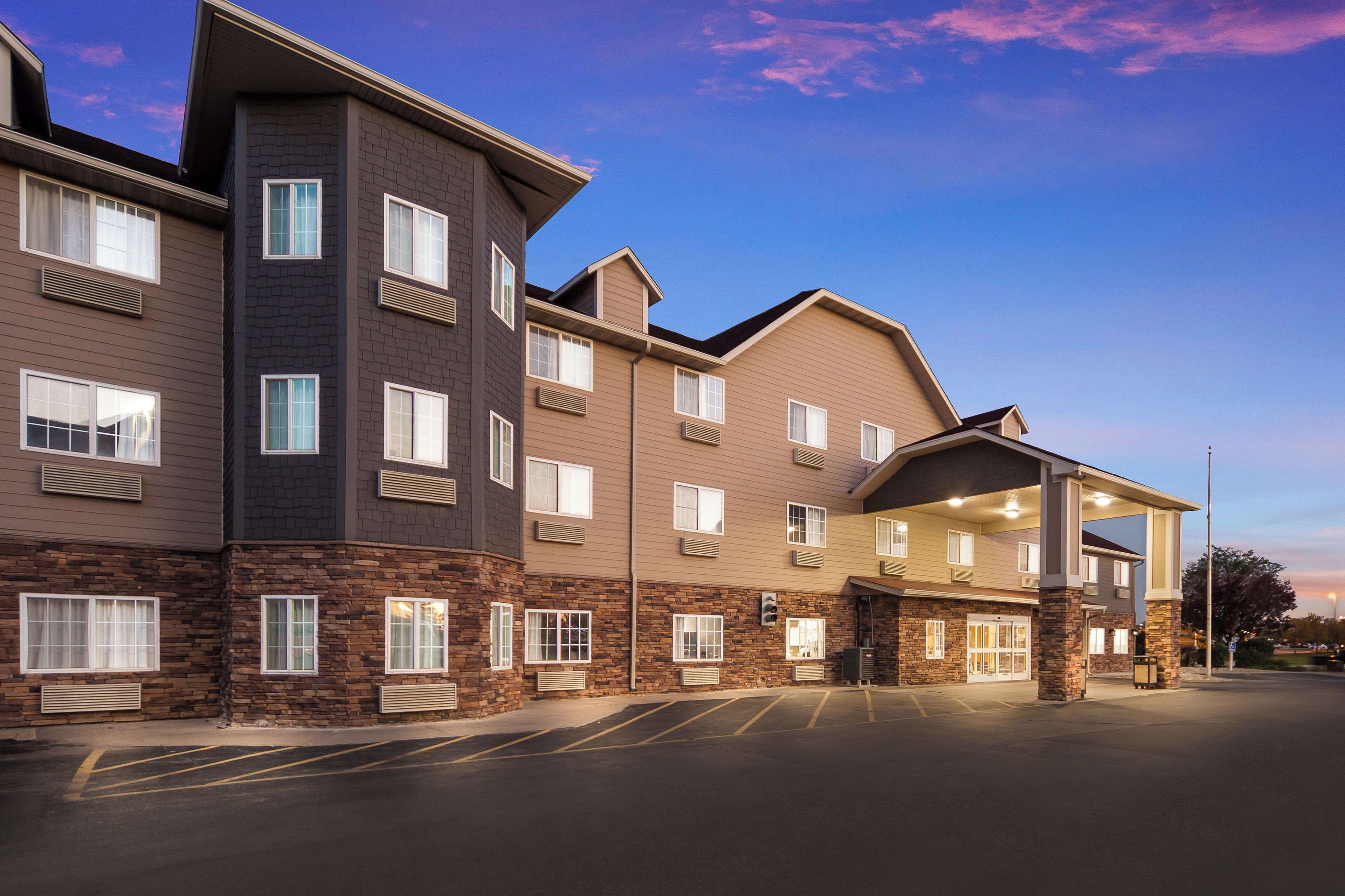 A multi-story hotel with a stone facade, multiple balconies, and a parking lot.