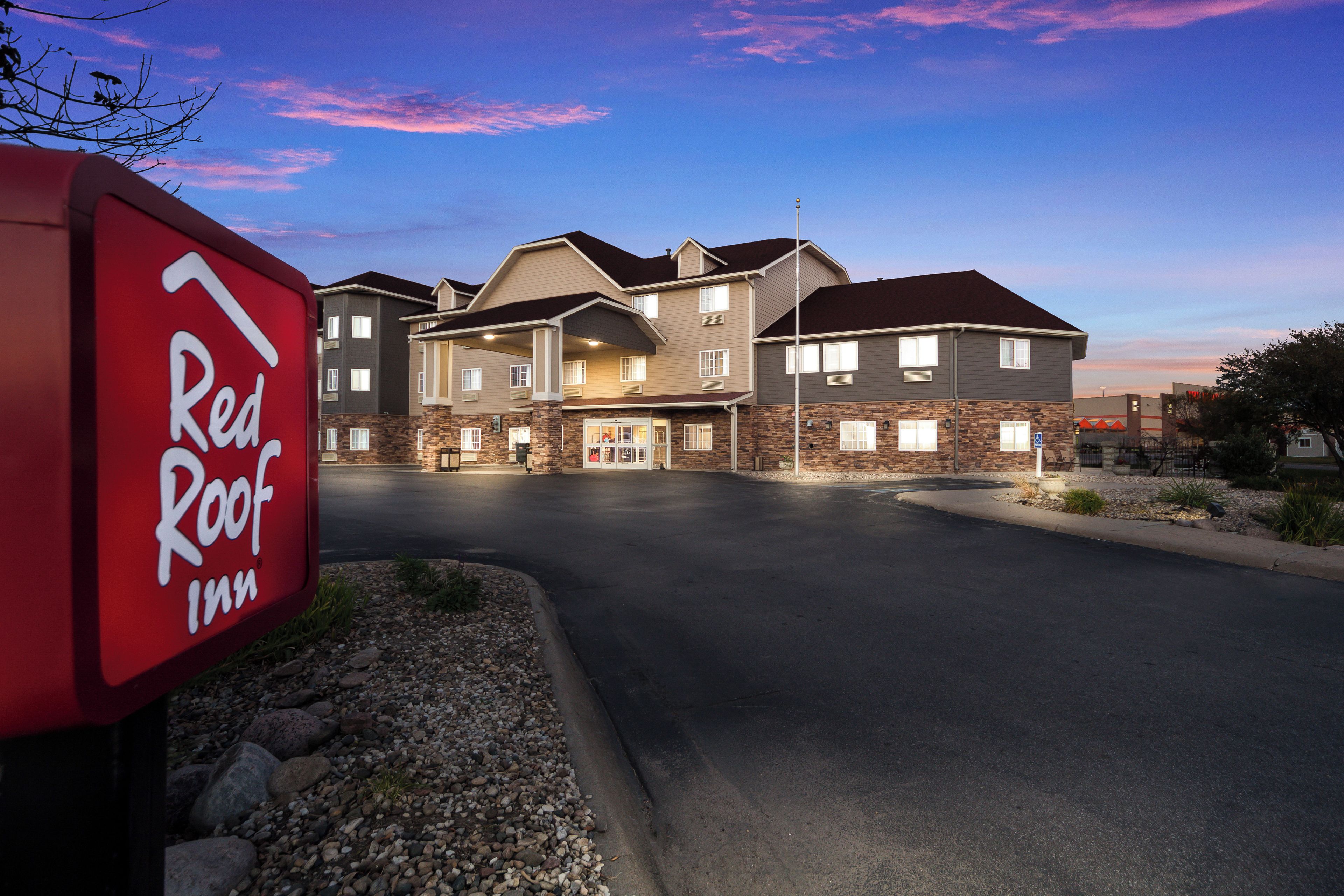 Un edificio de varios pisos con un letrero rojo que indica un Red Roof Inn.