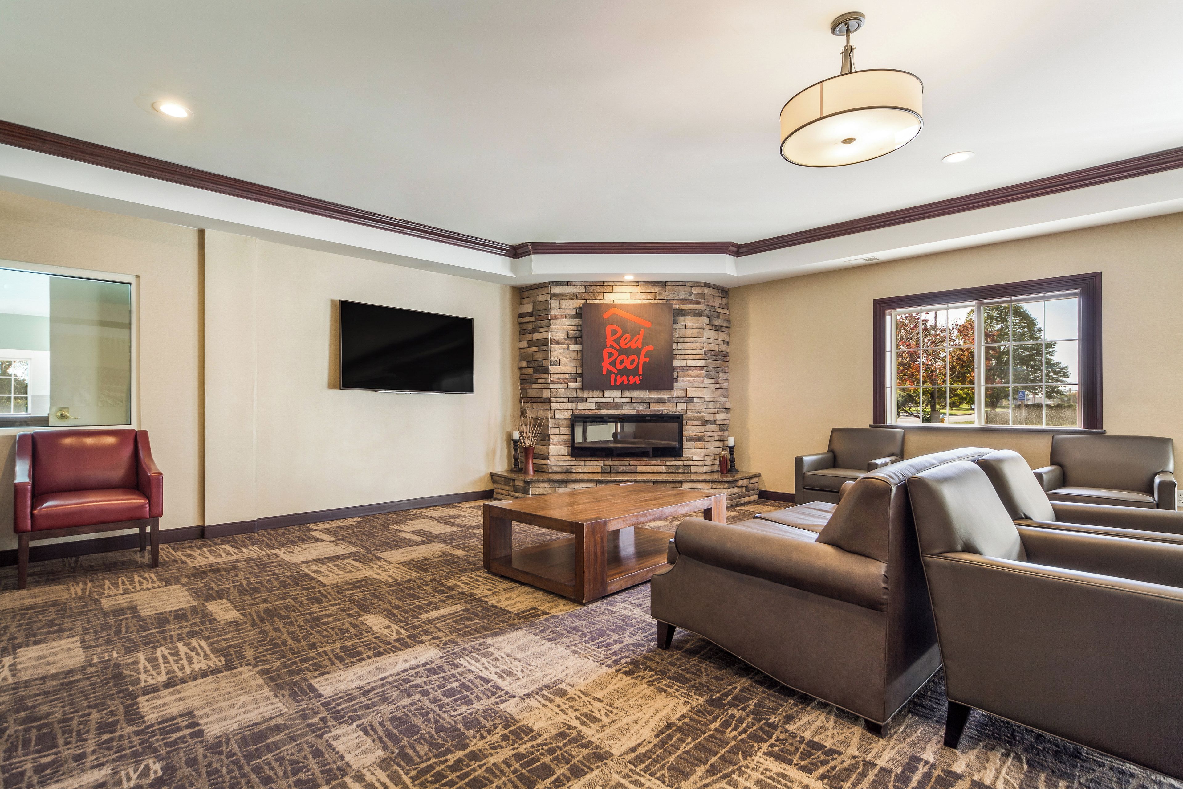 A living room with a stone fireplace, leather sofas, a flat-screen TV, and a patterned carpet.