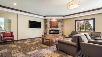 A living room with a stone fireplace, leather sofas, a flat-screen TV, and a patterned carpet.