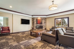 A living room with a stone fireplace, leather sofas, a flat-screen TV, and a patterned carpet.