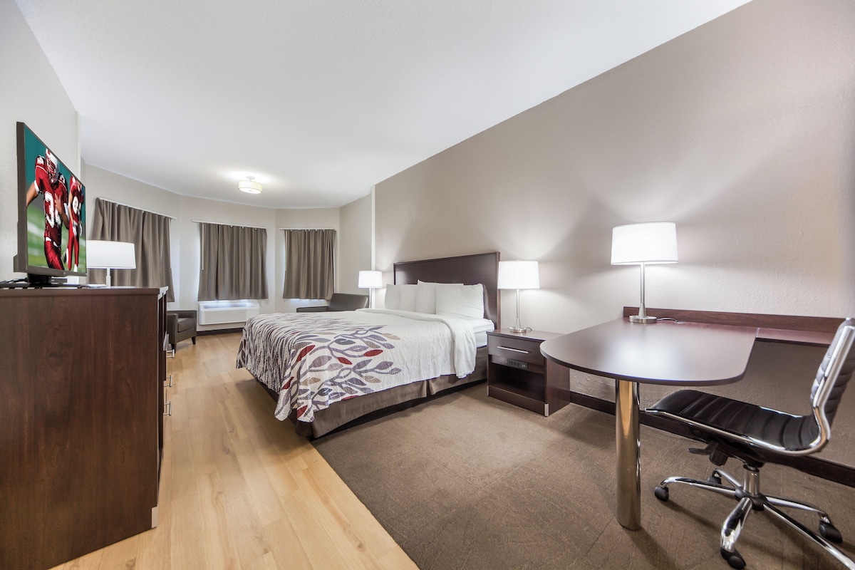 Une chambre d’hôtel comprenant un lit, des tables de chevet, un bureau, une chaise et un téléviseur.