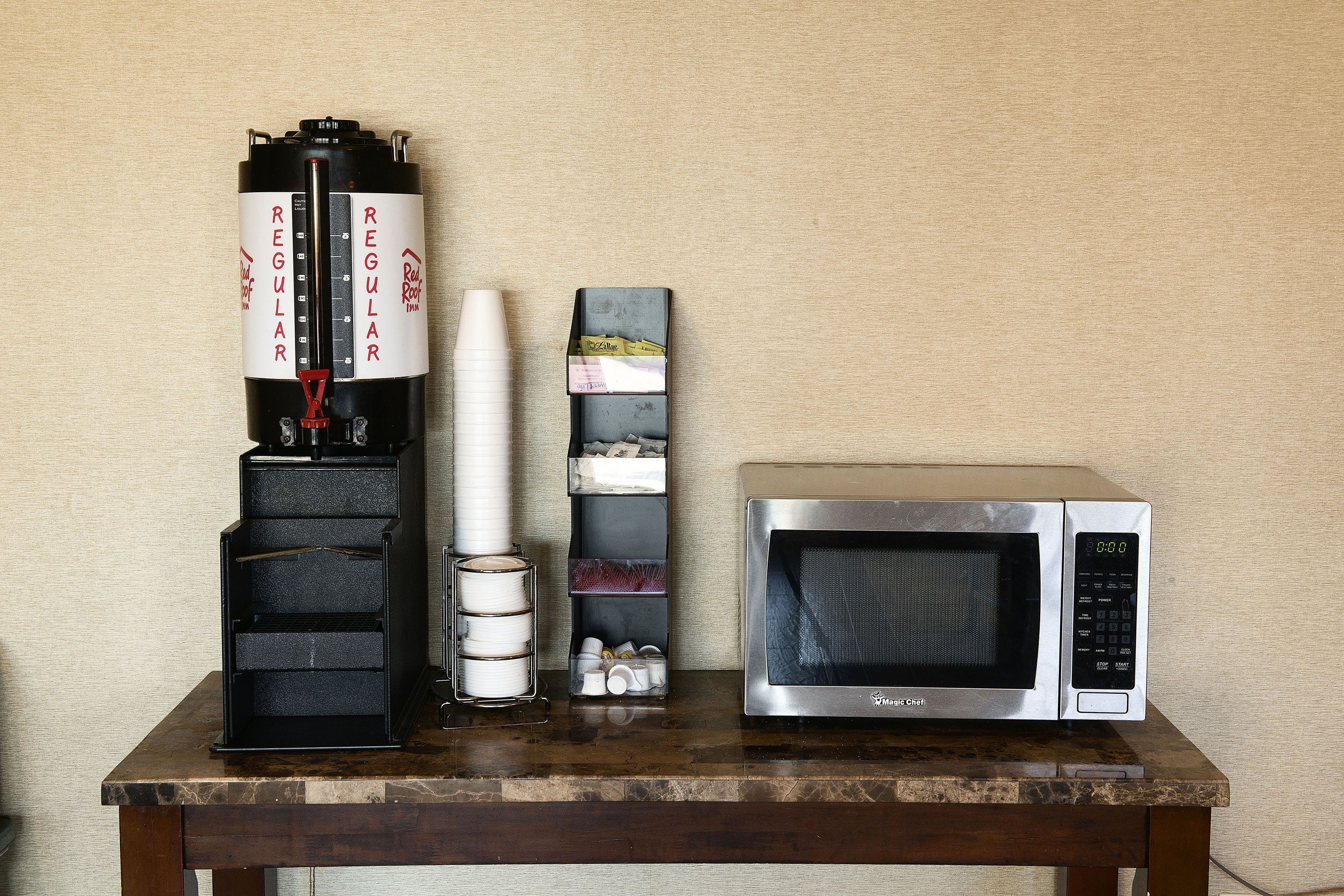 A kitchen counter with a coffee maker, a microwave, and a stack of plates.