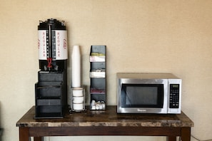 A kitchen counter with a coffee maker, a microwave, and a stack of plates.